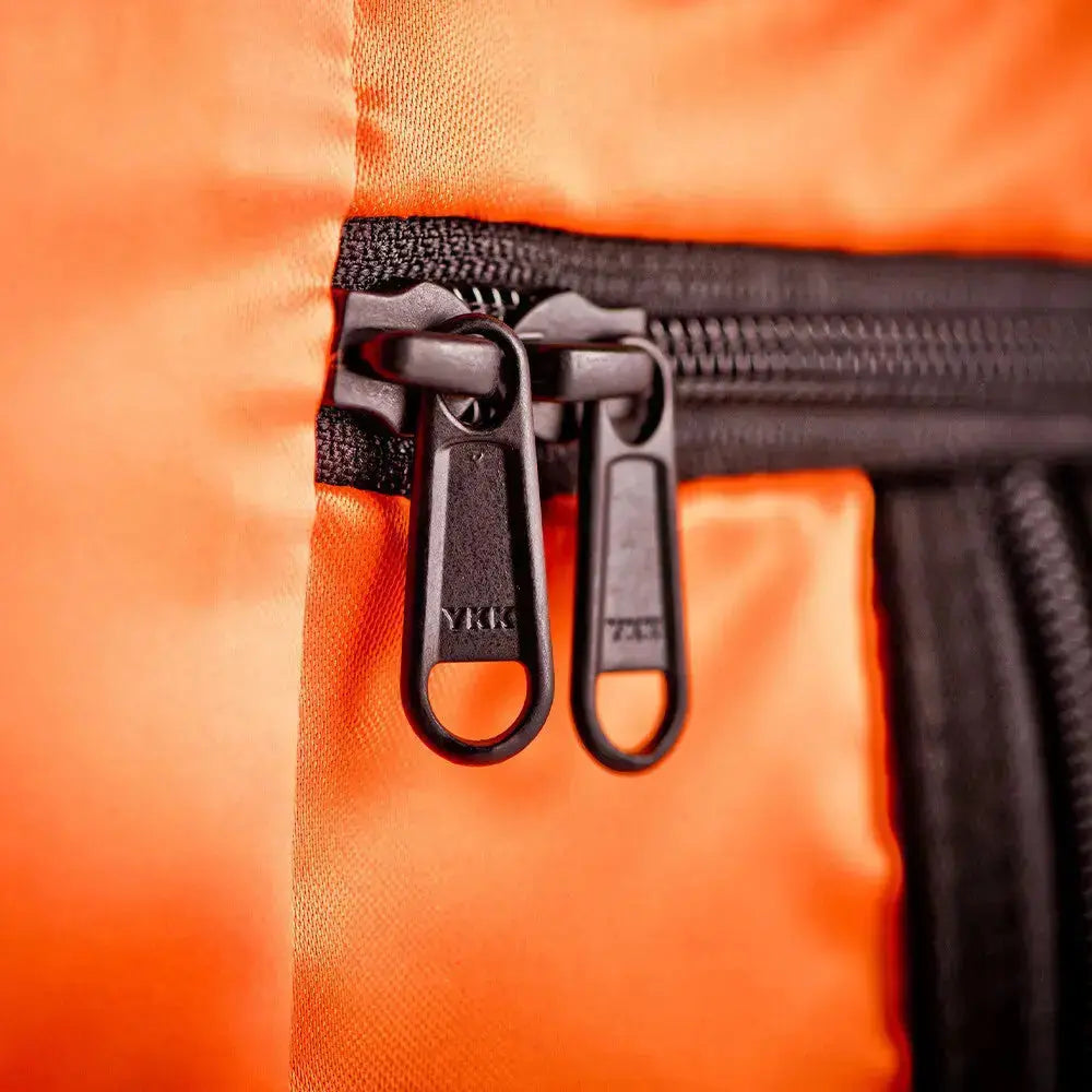 Close-up of orange Floyd travel case lining with black YKK zippers